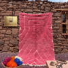 Handwoven Mrirt rug with pink geometric pattern in Moroccan outdoor setting